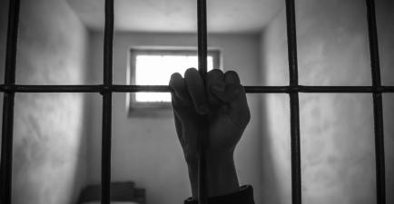 A prisoners hand holding prison bars