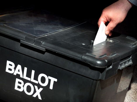 hand placing vote in ballot box